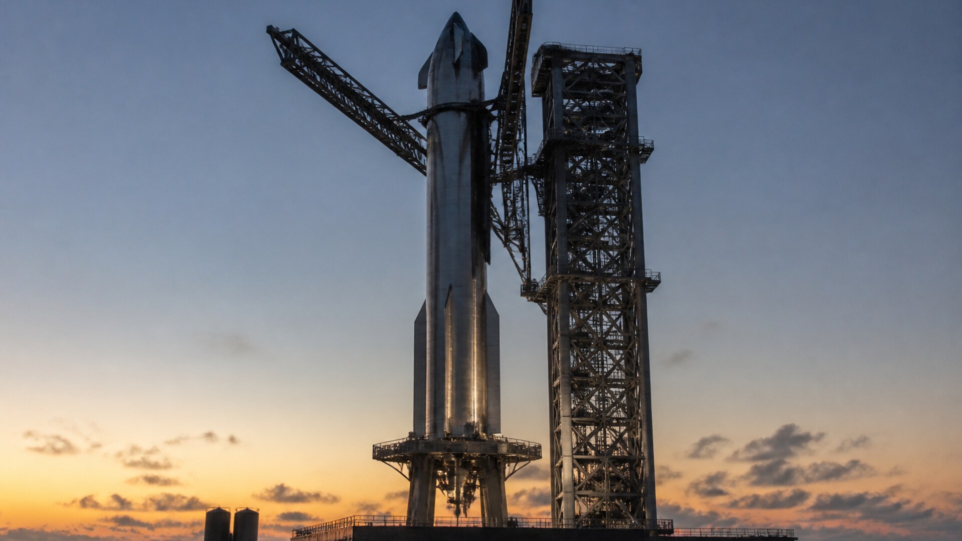 Stacked stainless Starship beside the catch tower at dusk